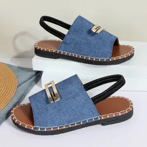 Vue détaillée des sandales plates chic en denim bleu avec boucle dorée et coutures