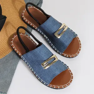 Vue de dessus de sandales plates en denim bleu avec boucle dorée et coutures blanches