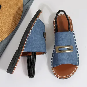 Détail rapproché de sandales élégantes en denim bleu avec une boucle dorée décorative.