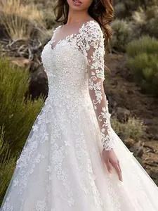 Close-up of elegant white wedding dress with intricate floral lace sleeves and bodice detail.