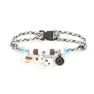 Close-up detail of a pet collar featuring a cute cat charm, fish pendant and black bell