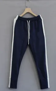 Detail view of navy blue men's sports joggers with white side stripe panels.