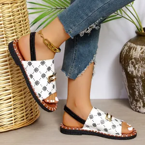 Gros plan de sandales plates blanches pour femmes avec motifs géométriques et boucle dorée chic