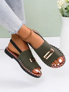 Détail de sandales plates vert olive avec boucle dorée portées par un mannequin