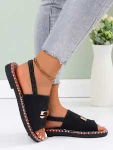 Détail de sandales plates noires pour femmes avec une boucle en métal dorée