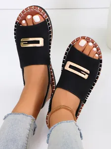 Gros plan de sandales plates noires pour femmes avec boucle dorée et surpiqûres
