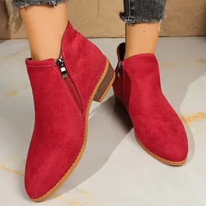 Close-up of women's red suede ankle boots featuring dual side zippers and chunky heels