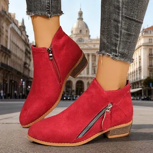 Red suede women's ankle boots with side zippers and low block heels in city setting