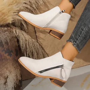 Close-up detail of off-white faux suede ankle boots featuring double side zippers and block heels.