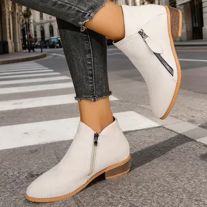 Side view of stylish off-white women ankle boots with double zippers and chunky low heel