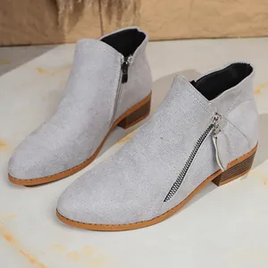 Close-up view of grey faux suede ankle boots with dual zippers and low chunky heel