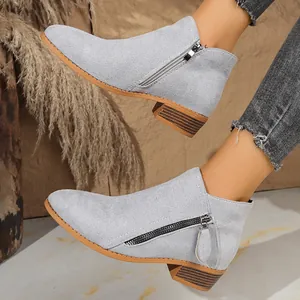 Detail view of gray suede-like ankle boots featuring dual side zippers and chunky heel.