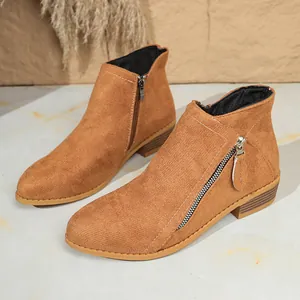 Close-up detail of women's brown suede ankle boots with stylish double side zippers