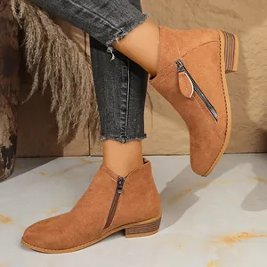 Detail view of women's suede ankle boots featuring dual side zippers and a chunky low heel.