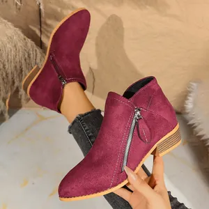 Close-up of wine red suede ankle boots with functional side zippers and block heels