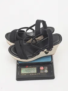 Detail view showing weight of black wedge sandals on digital scale