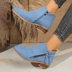 Close-up detail of light blue suede ankle boots with double side zippers and wood grain heels