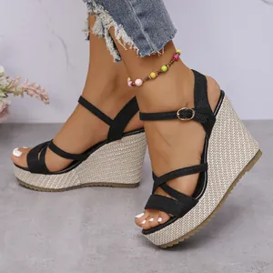 Detailed view of black cross strap wedge sandals featuring a woven hemp rope platform sole.