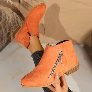 Detail of orange suede ladies ankle boots with double side zippers and chunky heel