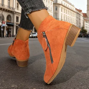 Close-up of vibrant orange suede ankle boots with block heel and side zipper detail.