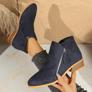 Close-up of navy blue suede ankle boots featuring double side zippers and chunky heels.