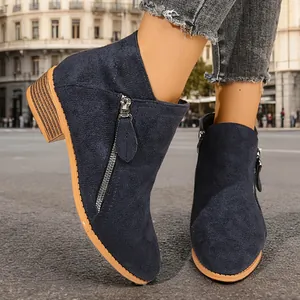 Detailed macro view of navy blue suede ankle boots featuring double metal side zippers