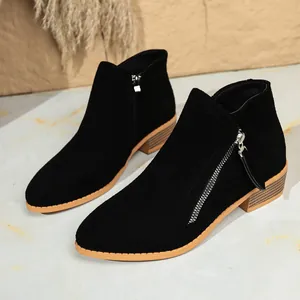 Detail view of black suede ankle boots with double side zippers and wood grain heel.