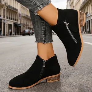 Close-up of black suede ankle boots with dual zippers and low stacked heel