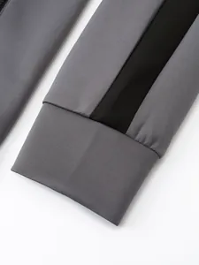 Detailed close-up of a grey tracksuit sleeve featuring a black stripe and ribbed cuff