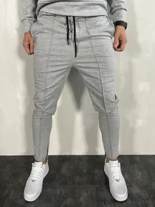 Dettaglio dei pantaloni sportivi grigi slim fit da uomo con coulisse e zip sul fondo