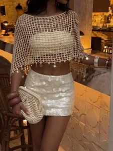 Gros plan sur un cache-maillot de plage au crochet beige avec des sequins dorés pendants