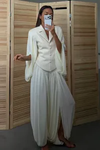Elegant cream blazer with dramatic bell sleeves and matching pleated lantern trousers set.