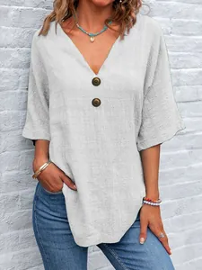 Dettaglio di una camicetta casual bianca in cotone e lino con scollo a V e bottoni marroni.