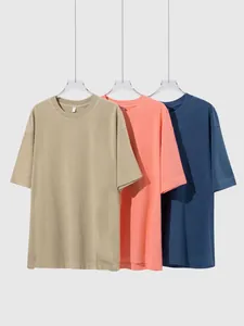 Three vintage washed cotton t-shirts in khaki, coral, and navy on hangers.