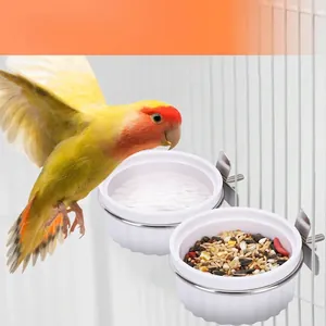 Detailed view of white bird feeding bowls for cages, featuring a parrot and bird seeds.