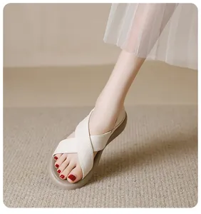 Close-up detail shot of ivory white cross-strap flat sandals featuring soft soles