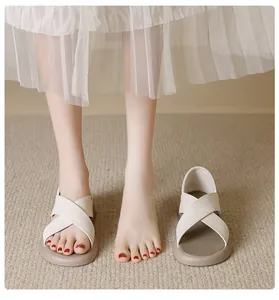 White cross-strap flat sandals for women shown being worn for summer beach wear