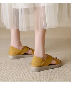 Detailed close-up of yellow pebble-grain leather flat sandals for women on carpet.