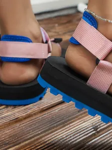 Dettaglio dei cinturini in velcro rosa e suola platform blu su questi sandali da mare