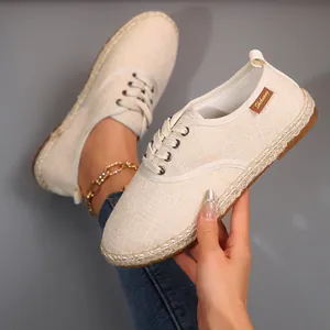 Detailopname van beige canvas espadrilles met witte veters en geweven details
