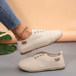 Detail van beige canvas espadrilles met jute zool en bruin merklabel.