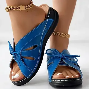 Close-up of blue peep-toe sandals featuring a decorative butterfly bow and cut-out design
