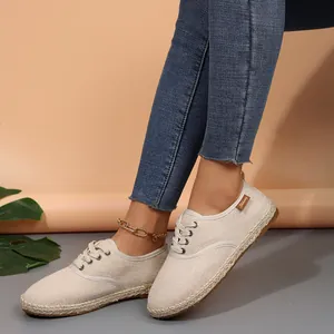 Close-up detail van beige canvas espadrilles voor dames met een geweven jute zool en veters.