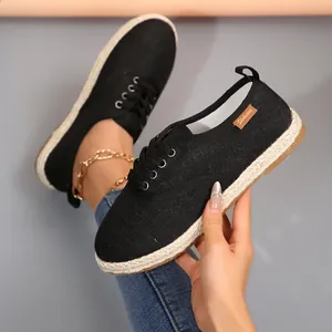 Detailweergave van zwarte canvas espadrille met touwzool en zijlabel van het merk