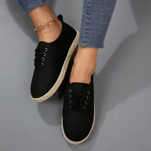 Close-up van zwarte canvas espadrilles met jute zool en vetersluiting