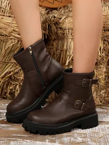 Detail of brown women's retro motorcycle boots with buckle straps and platform lug sole.