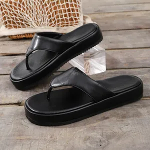 Vista detallada de chanclas con plataforma negras con suela gruesa y textura de cuero sintético.