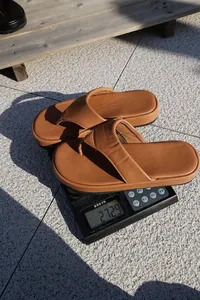 Vista detallada de chanclas marrones de suela gruesa para mujer pesadas en una báscula.