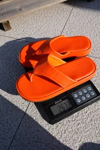 Detalle de sandalias de plataforma naranja en una báscula mostrando su peso