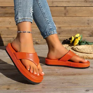 Primer plano de sandalias con plataforma naranja vibrante en un suelo de madera rústica